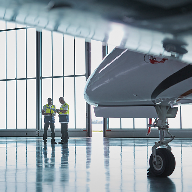 Dois mecânicos de aeronaves no hangar com jato