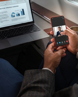 Business person using a cellphone and laptop on aircraft
