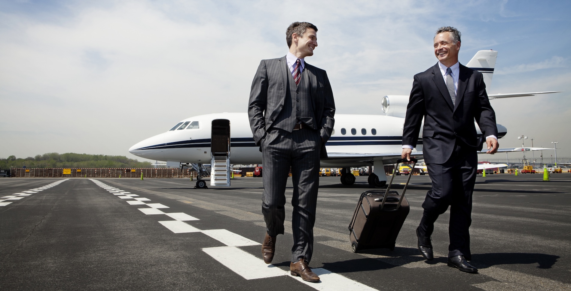 Two men walking away from a private jet on the tarmac