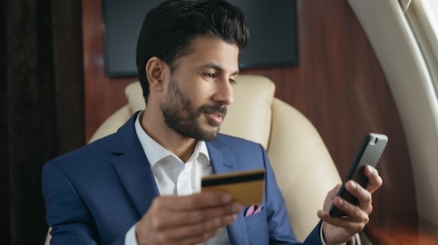 Homem segurando um telefone e cartão de crédito