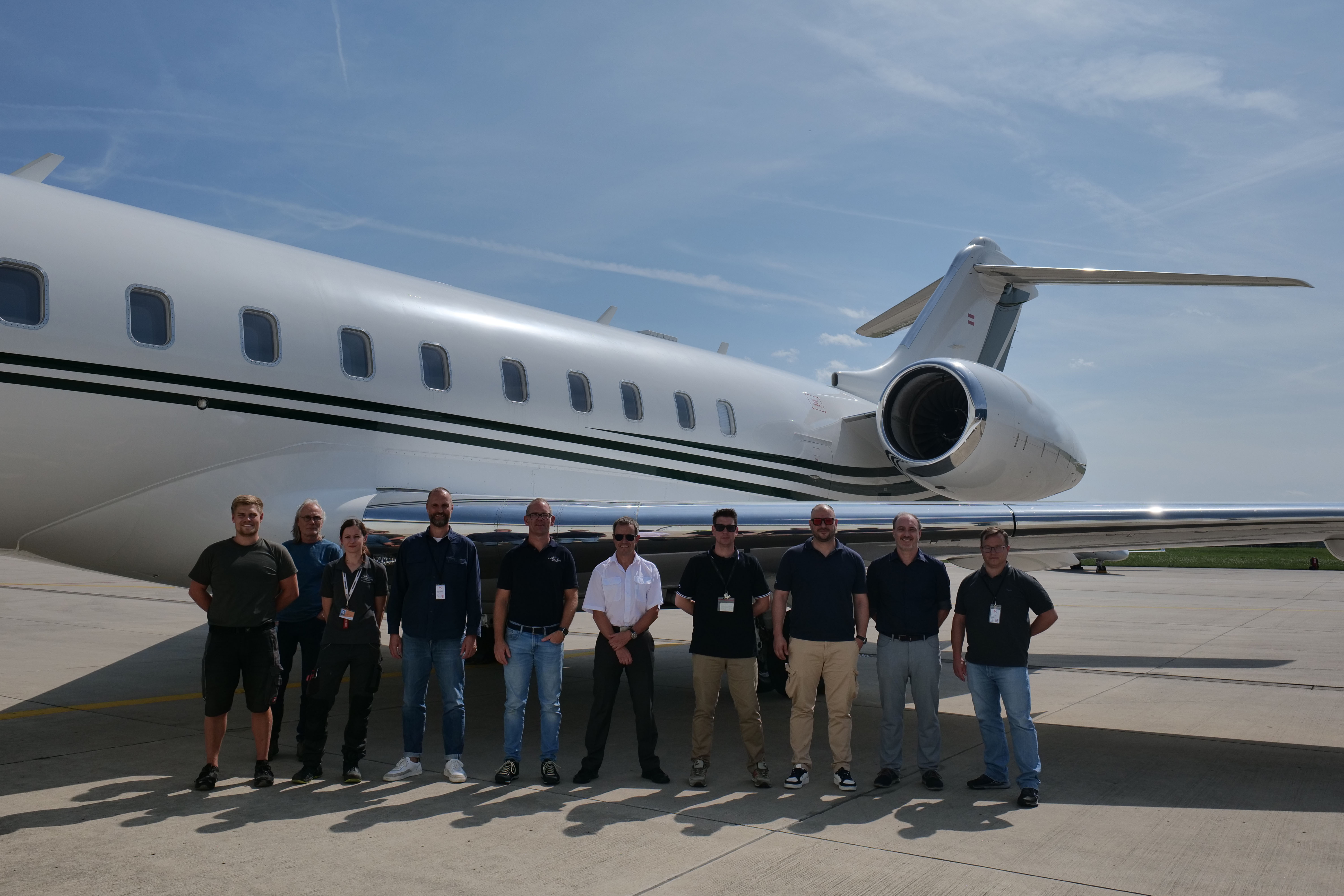 People standing in front of Bombardier Global jet with HDX antenna installed