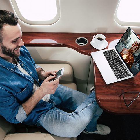 Smiling passenger wearing headphones connected to phone