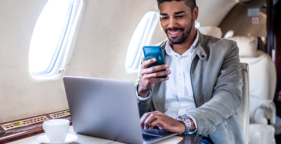Man checking phone while on laptop in cabin