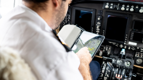 Pilot looking at maps on tablet in cockpit